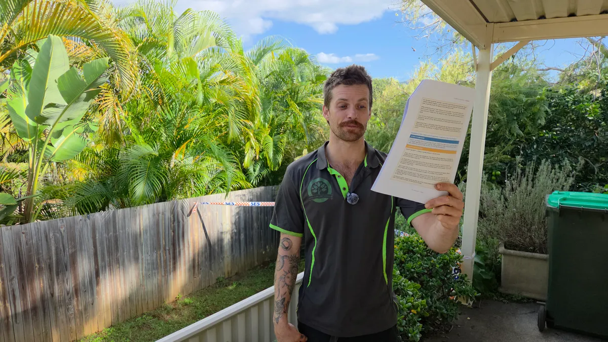 Casey Grimes, AQF Level 3 arborist and owner of Tweed Coast Tree Surgeons, holding a council approval document on a site visit